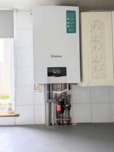 Engineer fitting a wall-mounted boiler